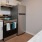 Spacious and well lit kitchen with wood floors and stainless steel appliances. 